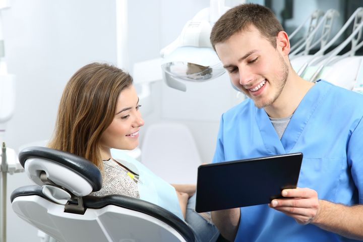 Happy,Dentist,And,Patient,Commenting,Treatments,In,A,Tablet,Application